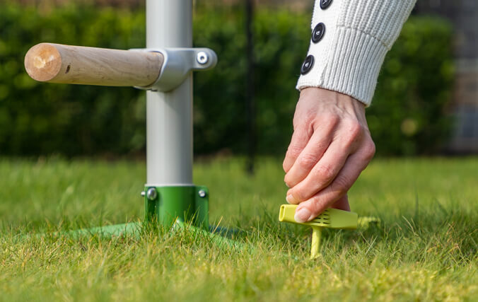 The ingenious design and the high quality materials makes this a future-proof perch tree. Woman securing the free standing chicken perch into your lawn with easy to use screw pegs