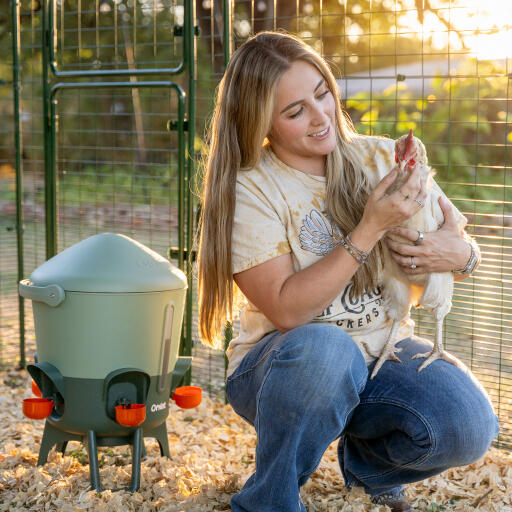 woman holding chicken next to the omlet insulated chicken waterer